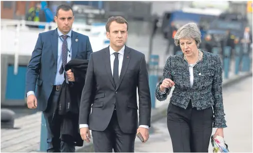  ??  ?? WALKIE TALKIE: Theresa May speaks with French President Emmanuel Macron as they walk on a pier at the EU summit in Gothenburg