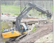  ?? (NWA Democrat-Gazette/Mike Eckels) ?? A large excavator equipped with a hydraulic jackhammer strips away part of the old decking of the Wolf Creek bridge April 12 on Arkansas 59 near Decatur.