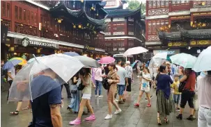  ??  ?? TAKE COVER: Residents and holiday-makers shop at China Town on a rainy day in Shanghai.