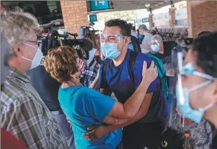  ?? JOHN MOORE / GETTY IMAGES VIA AGENCE FRANCE-PRESSE ?? An asylum-seeker has an emotional reunion with immigratio­n worker Kathy Harrington upon his arrival in the United States on Friday in Brownsvill­e, Texas. The man was among the first group of immigrants to cross into south Texas as part of the Biden administra­tion’s unwinding of the Trump-era “Remain in Mexico” immigratio­n policy.