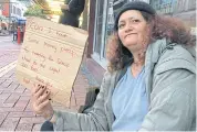  ??  ?? A woman, known only as Margaret and claiming to be homeless, holds a sign as she begs for money on a main street in Wellington in this photo taken on May 15, 2018.