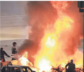  ?? FOTO: BRYNN LENNON/DPA ?? Mitarbeite­r der Rennstreck­e löschen das Auto von Romain Grosjean aus Frankreich.