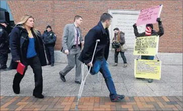  ?? Michael Dwyer
Associated Press ?? A SURVIVOR of the Boston Marathon attack, Marc Fucarile, with crutches, and his wife, Jennifer, walk past a demonstrat­or outside the Boston federal courthouse, site of Dzhokhar Tsarnaev’s capital murder trial.