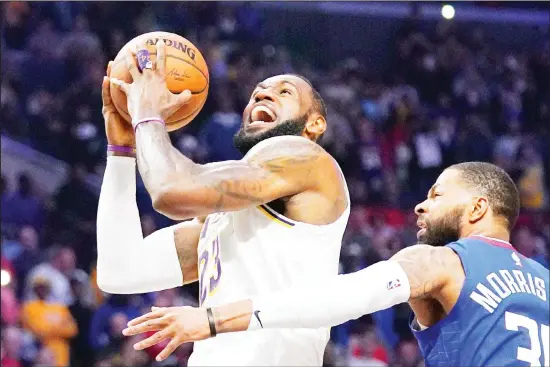  ??  ?? In this March 8, 2020 file photo, Los Angeles Lakers forward LeBron James (left), shoots as Los Angeles Clippers forward Marcus Morris Sr defends during the second half of an NBA basketball
game in Los Angeles. (AP)