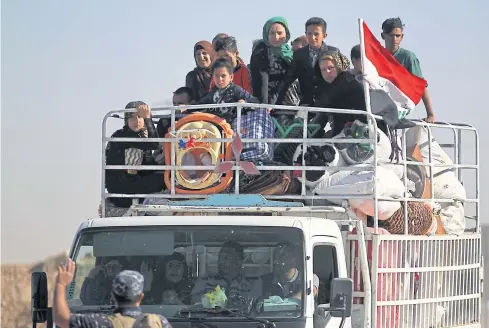  ?? AFP ?? Displaced Iraqis who fled from Hawija in 2014 to Kirkuk ride in a vehicle on Oct 17 as they return to Hawija, after the town was retaken by the Iraqi forces from Islamic State fighters.