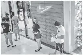  ??  ?? (Above) customers will have to get used to waiting in long lines for their needs and wants. (Left) social distancing measures are observed inside a mall in Cainta, Rizal.