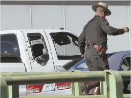  ?? AP PHOTO ?? AFTERMATH: A policeman walks past a white pickup truck with multiple bullet holes in the windows at the scene of a shooting on Interstate 95 in Providence yesterday.