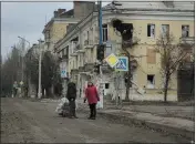  ?? TYLER HICKS — THE NEW YORK TIMES ?? Pedestrian­s survey battle-damaged buildings in Bakhmut, a frontline city that continues to weather Russian attacks, in the Donbas region of Ukraine on Saturday.