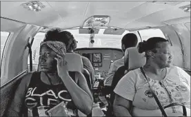  ?? FERNANDO LLANO/AP ?? Dimple Lightbourn­e, left, and her mother, Carla Ferguson, sit in a plane Monday as it approaches to land in Nassau after they were evacuated from Abaco Island, in the Bahamas.