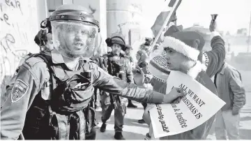  ??  ?? A Palestinia­n dressed as Santa Claus argues with an Israeli border police during clashes in the West Bank city of Bethlehem. — Reuters photo