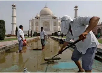  ?? SAUMYA KHANDELWAL / REUTERS ?? Laborers clean the fountain in the historic Taj Mahal premises in Agra, India, on Saturday.