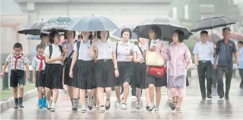  ??  ?? A group of students walk through the rain to pay their respects to late North Korean leaders Kim Il-Sung and Kim Jong-Il outside Kumsusan Palace as the country marks ‘Victory Day’ in Pyongyang. — AFP photo