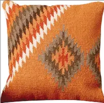  ?? Associated Press photos ?? This undated photo provided by AllModern shows their pillow using rich, earthy hues and bold geometrics which make for this striking and sturdy piece. Kilim rug weaves are trending off the floor, in pillows and upholstery, as part of the global and...