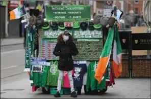  ?? (AP/Peter Morrison) ?? A souvenir seller waits for customers Tuesday in Dublin after Irish authoritie­s called off the St. Patrick’s Day parade. The event usually draws half a million people. More photos at arkansason­line.com/318stpat/.