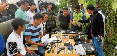  ?? —PNP HIGHWAY PATROL GROUP BICOL ?? CHECKPOINT SEIZURE A police team at a checkpoint in Camarines Sur province makes an inventory of guns, explosives and other items seized from two suspects in the killing of Mayor Ferdinand Bote of General Tinio, Nueva Ecija.