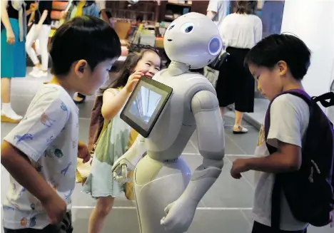  ?? SHIZUO KAMBAYASHI/THE ASSOCIATED PRESS ?? Children surround SoftBank’s companion robot Pepper at a Tokyo store. Pepper offers dance moves, small talk and can detect human faces.