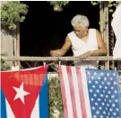  ??  ?? Un hombre coloca las banderas de EE.UU. y Cuba en su balcón.