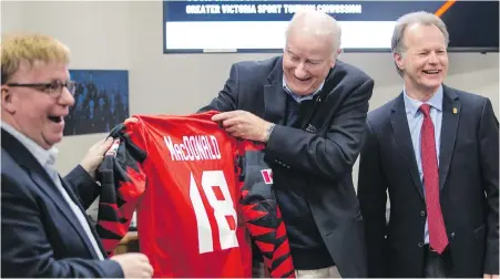  ??  ?? Retiring SportHost Victoria executive director Hugh MacDonald, centre, receives a jersey from Tourism Victoria CEO Paul Nursey, left, and PISE CEO Robert Bettauer during a sport-tourism organizati­on announceme­nt at Saanich Commonweal­th Place.