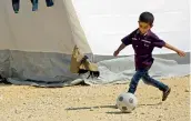  ?? — AFP ?? A Syrian boy kicks a ball in a camp for displaced Syrians from the former rebel bastion of Douma, in alBil, east of the rebel- held town of Azaz in northern Syria on Friday.