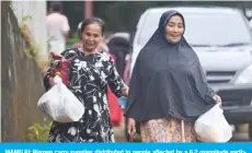  ??  ?? MAMUJU: Women carry supplies distribute­d to people affected by a 6.2 magnitude earthquake in Mamuju yesterday. — AFP