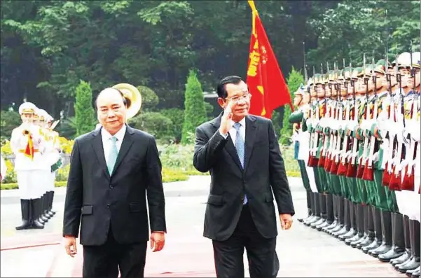  ?? HUN SEN’S FACEBOOK PAGE ?? Prime Minister Hun Sen waves alongside Vietnamese counterpar­t Nguyen Xuan Phuc as he inspects a guard of honour in Hanoi.