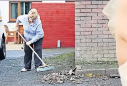  ?? ?? A neighbour sweeps fragments of tiles and bricks in street