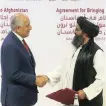  ?? AP ?? US PEACE envoy Zalmay Khalilzad, left, and Mullah Abdul Ghani Baradar, the Taliban’s top political leader, shake hands after signing a peace agreement in Qatar yesterday. |