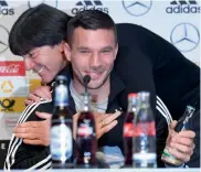  ?? — AFP ?? Germany’s Lukas Podolski gets a hug from coach Joachim Loew at a press conference. Left: England midfielder Adam Lallana at a training session.