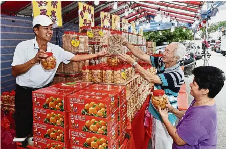  ??  ?? Savoury biscuits: Customers buying cookies from Lim at his stall in Jalan Badik 1, Johor Baru.