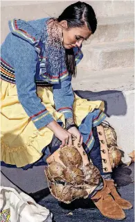  ?? [PHOTO PROVIDED] ?? Cotie Poe, of Millcreek, prepares elements of her traditiona­l, Native American clothing, during a performanc­e at the closing event for Native American Heritage Month in 2017.