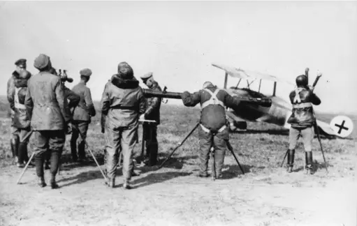  ??  ?? ■ Suited up and ready for immediate take-off, pilots of Jasta 11 search for enemy aeroplanes from Cappy airfield in April/may 1918. Most are wearing harnesses for the Heinecke parachute, a fairly recent innovation. They are using optical instrument­s developed for Flak crews to determine the height and range of hostile aircraft.