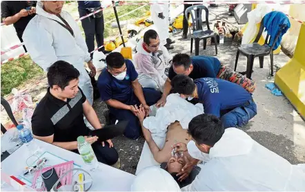  ??  ?? Perils of the job: A DOE employee being treated by medical staff after he collapsed while carrying out checks around Sungai Kim Kim in Pasir Gudang.