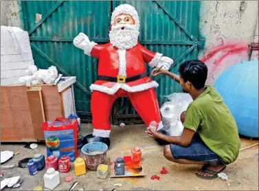  ?? REUTERS ?? An artisan applies finishing touches to a Santa Claus model made of polystyren­e, at a workshop in Kolkata on Thursday.