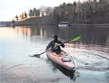  ?? PAUL A. SMITH ?? Mick Lewski of Oak Creek paddles his kayak away from the public access on Beaver Lake in Hartland as he prepares to catch up to Isaiah Wolk of St. Francis (left background) on opening day of the Wisconsin fishing season.