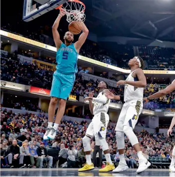  ?? AP ?? Nicolas Batum ( left) of Charlotte Hornets dunks over Myles Turner and Victor Oladipo of Indiana Pacers in their NBA game in Indianapol­is on Monday. The Pacers won 105- 96. —