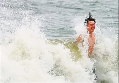  ?? Christian Abraham / Hearst Connecticu­t Media ?? Eric (last name not given) braces himself against a crashing wave as he and two buddies play in the surf at Jennings Beach in Fairfield on Friday. A tropical storm hit the region Friday evening with winds from 35-45 mph and gusts up to 50 mph.