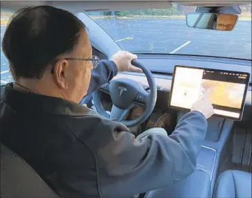  ?? Gillian Flaccus Associated Press ?? VINCE PATTON, a Tesla owner, demonstrat­es playing a video game this week while driving on a closed course in Portland, Ore. He said he worries that drivers will play games and become dangerousl­y distracted.