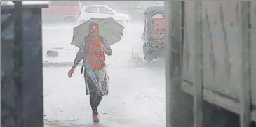  ?? HIMANSHU VYAS/ HT PHOTO ?? A woman walks as rains lash Jaipur. The rains have triggered landslides in some hill states in the country.