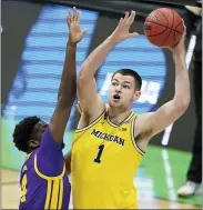  ?? DARRON CUMMINGS — THE ASSOCIATED PRESS ?? Michigan’s Hunter Dickinson, right, shoots over LSU’S Darius Days during Monday’s second-round NCAA Tournament game. Michigan won the game, 86-78. See the morningsun.com/sports for details.