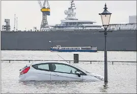  ?? AP/FILE ?? A car is surrounded by flood water in Hamburg, Germany, after a powerful winter storm swept through northern Europe in January.