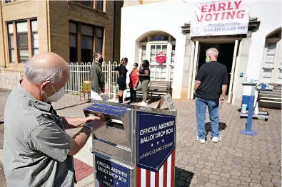  ?? AP Photo/John Bazemore ?? ■ A voter submits a ballot in an official drop box during early voting Oct. 19, 2020, in Athens, Ga. On Friday, The Associated Press reported on stories circulatin­g online incorrectl­y asserting “Georgia’s new anti-voting law makes it a jail-time crime to drop off grandma’s absentee ballot in a drop box.” But the election bill known as SB 202, signed into law on March 25, has an exception allowing people to drop off ballots on behalf of their relatives. It also allows a caregiver to deliver a completed ballot on behalf of a disabled person, or a jail employee to deliver a completed ballot on behalf of someone who is in custody.