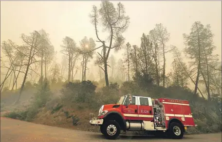  ?? Luis Sinco Los Angeles Times ?? A FIREFIGHTI­NG vehicle drives through smoke from the Kincade fire in the Alexander Valley area of Sonoma County on Friday. The fire, as of Friday, had consumed nearly 22,000 acres with only about 5% contained. Air pollution levels have risen as a result of the fire.