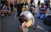  ?? GETTY IMAGES ?? People pray Sunday at the spot in Charlottes­ville, Va., where Heather Heyer, 32, was killed the day before when a car plowed into a crowd of people protesting against a white supremacis­t rally.