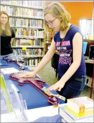  ?? Lynn Atkins/The Weekly Vista ?? Grace Martin tries out the "Makey Makey Rock Band" that the Amazeum staff brought to the the Bella Vista Library last week.