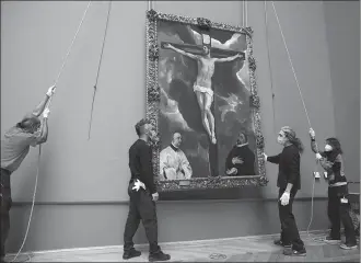  ?? THIBAULT CAMUS / AP ?? Workers at the Louvre hoist Christ on the Cross Adored by Two Donors back into position at the Paris museum on Tuesday. The El Greco work was returned from an exhibition.