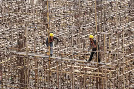  ?? STR/AGENCE FRANCE-PRESSE ?? WORKERS are seen on scaffoldin­g at a railway station constructi­on site in southweste­rn China’s Chongqing municipali­ty on 18 February 2024.
