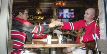  ??  ?? Jim Moore (left) and Tony Vittal enjoy a drink Friday at WestEnd before the Hawks’ victory against Edmonton.