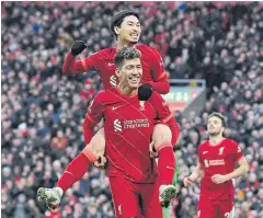  ?? AFP ?? Liverpool’s Takumi Minamino, top, celebrates with Roberto Firmino after scoring against Brentford in a Premier League game at Anfield on Sunday.