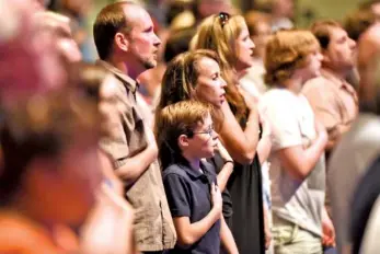  ??  ?? Abba’s House congregati­on members cover their hearts during the singing of the national anthem.