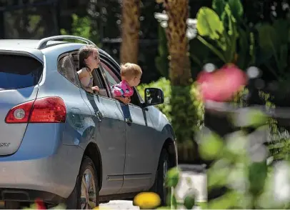  ?? Josie Norris / Staff Photograph­er ?? Children lean out of car windows to look at animals during a soft open of a drive-thru version of the San Antonio Zoo on April 30 in San Antonio. The zoo has announced it will open to the general public June 1.